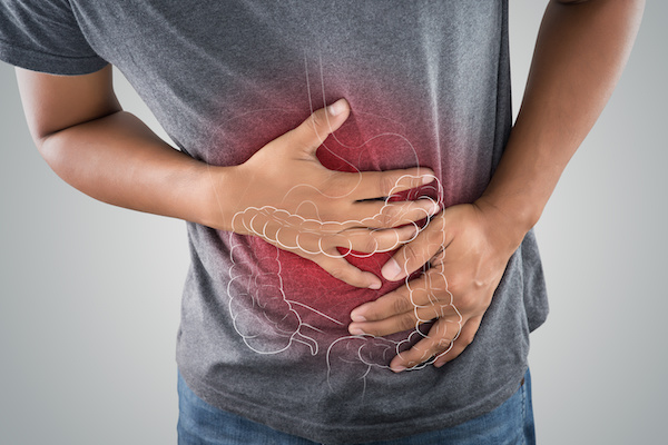Man in gray tshirt grabs stomach as red model of GI tract hovers above hands