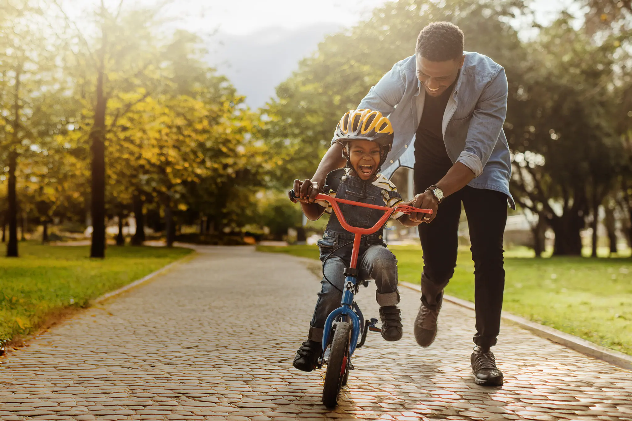 A man teaching a boy how to ride a bicycle.