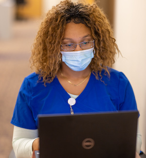 nurse with curly hair standing at workstation