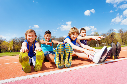 Happy kids doing stretching exercises on a track