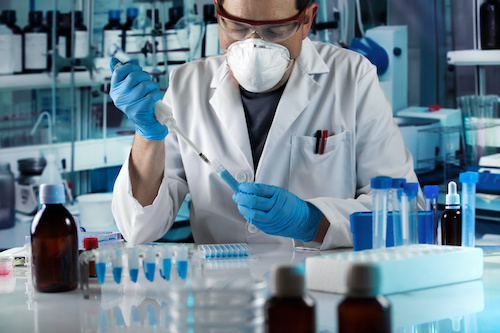 masked male researcher at lab table