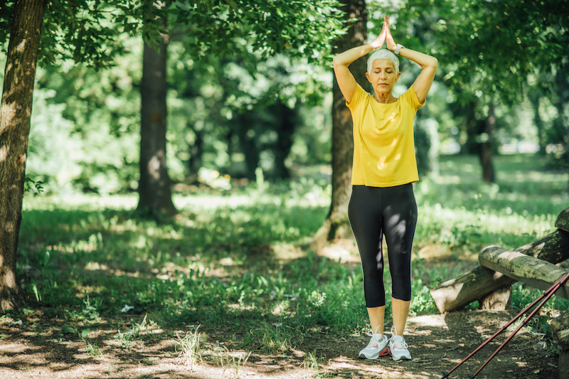 woman standing in a park doing a yoga pose