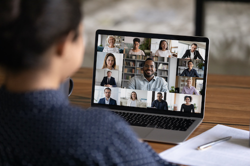 Over shoulder view of female worker have webcam digital virtual conference with diverse multiethnic colleagues. Woman speak talk on video call with multiracial businesspeople