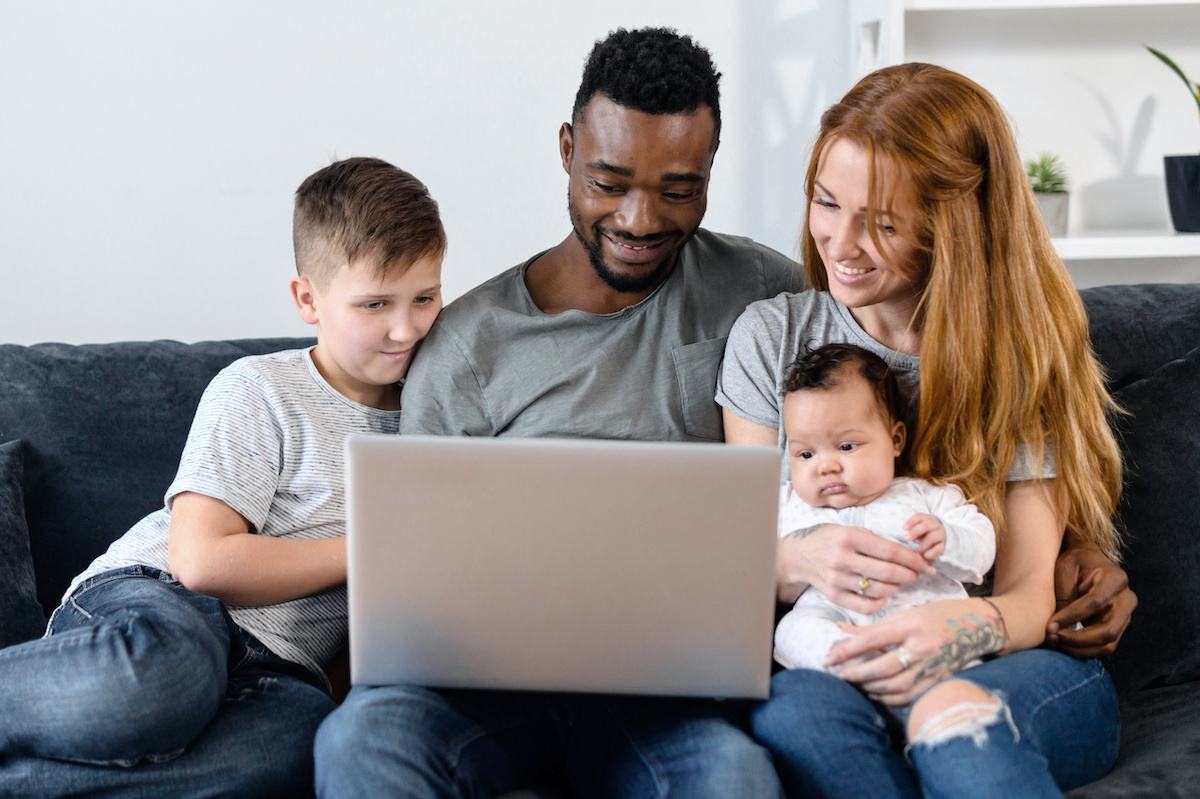 diverse family sitting on couch looking at laptop