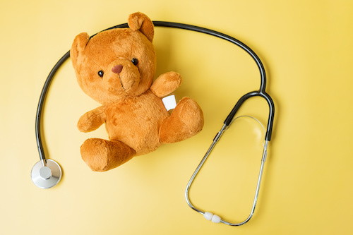 stethoscope and teddy bear on yellow background