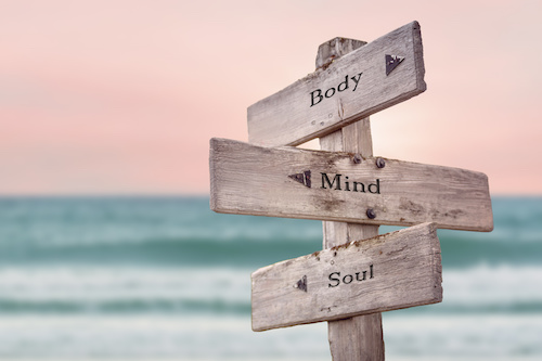 body mind soul text quote written on wooden signpost by the sea