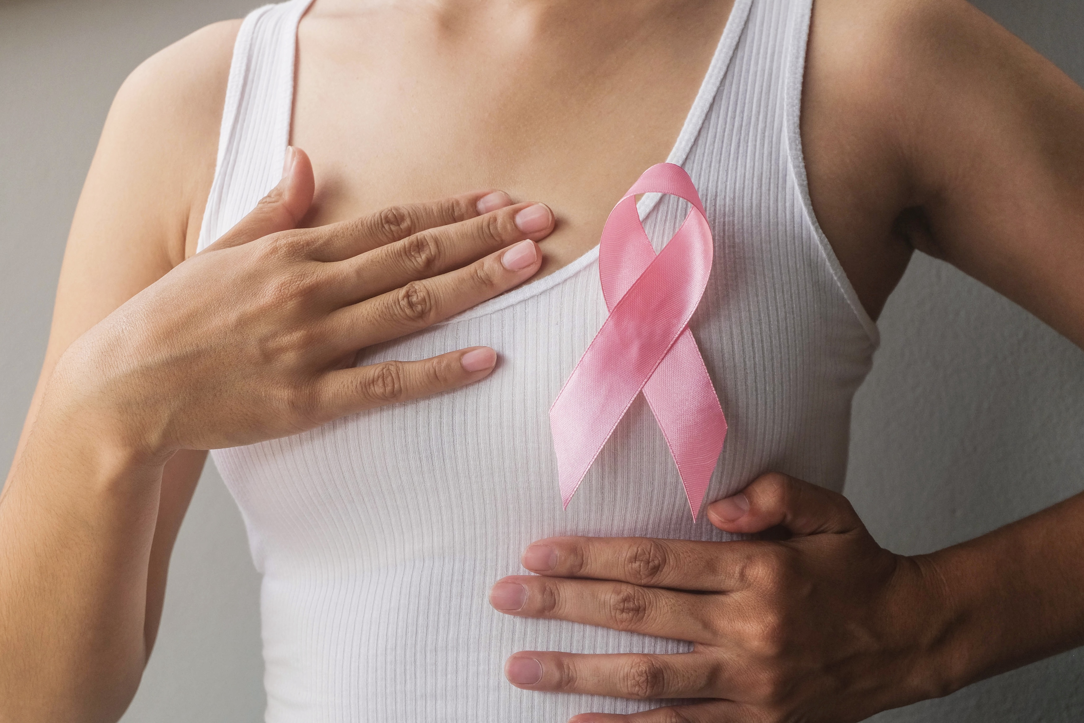 Black woman holds pink cancer ribbon in her palms