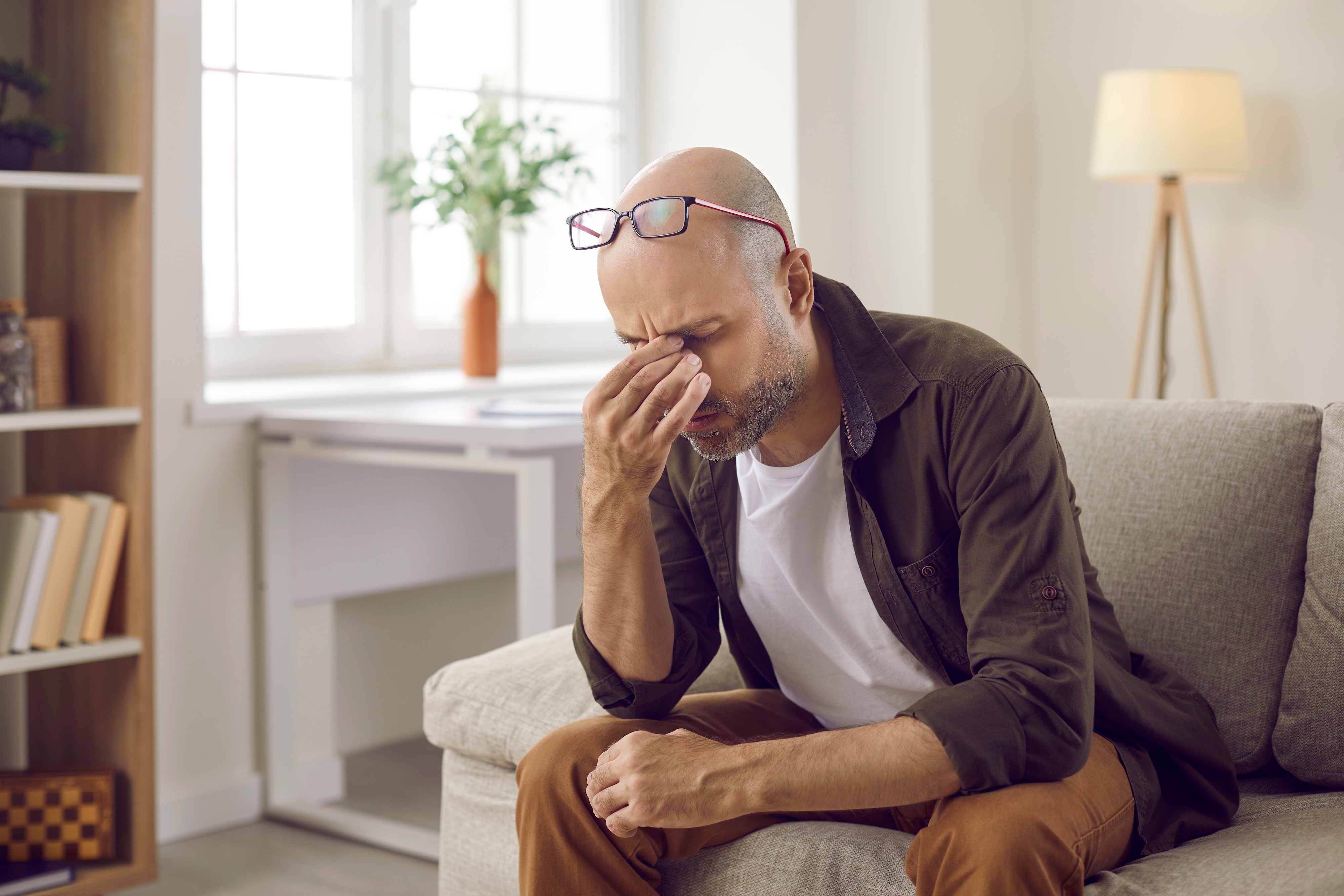 Man grabbing his forehead in discomfort from cancer related fatigue