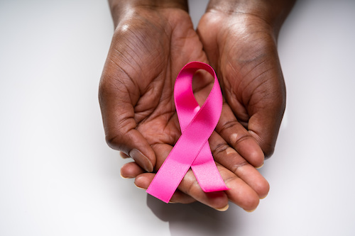 Black woman holds pink cancer ribbon in her palms