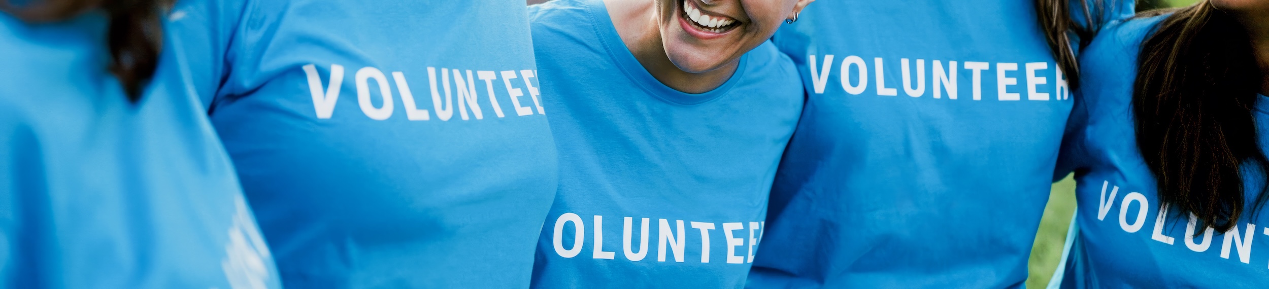 Close up of teens huddled together wearing blue volunteer t-shirts