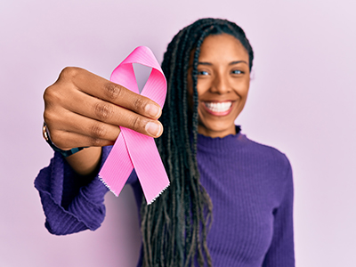 Woman holding pink breast cancer ribbon and smiling