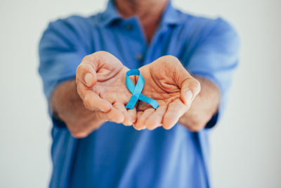 Person in blue collar shirt holding blue awareness ribbon in palm | Rutgers Cancer Institute of New Jersey