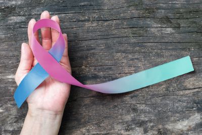Pink to blue gradient awareness ribbon in the palm of person's hand | Rutgers Cancer Institute of New Jersey