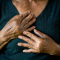 Old woman holding her hands to her chest on black background