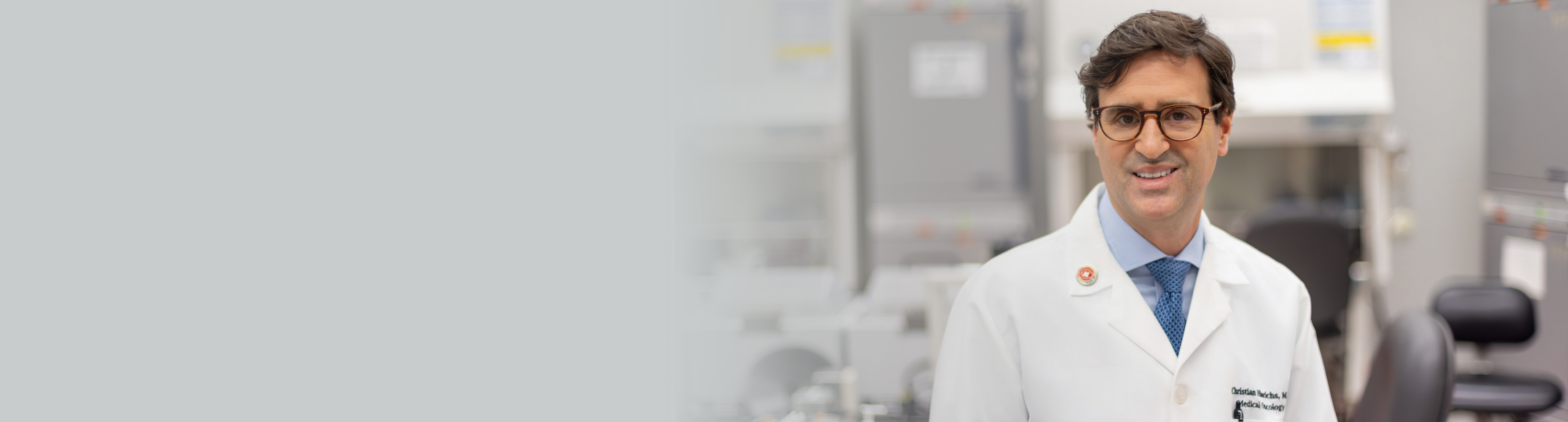 Dr. Christian Hinrichs in lab coat smiling at camera